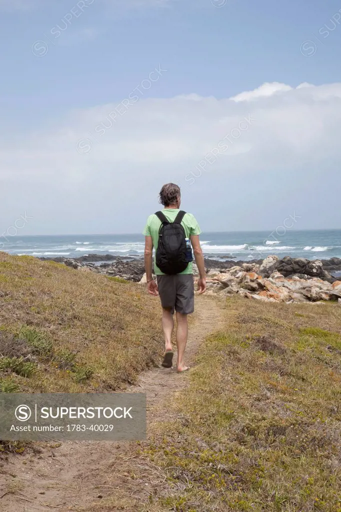 South Africa, Garden Route, Man walking in coastal area; Port Elizabeth