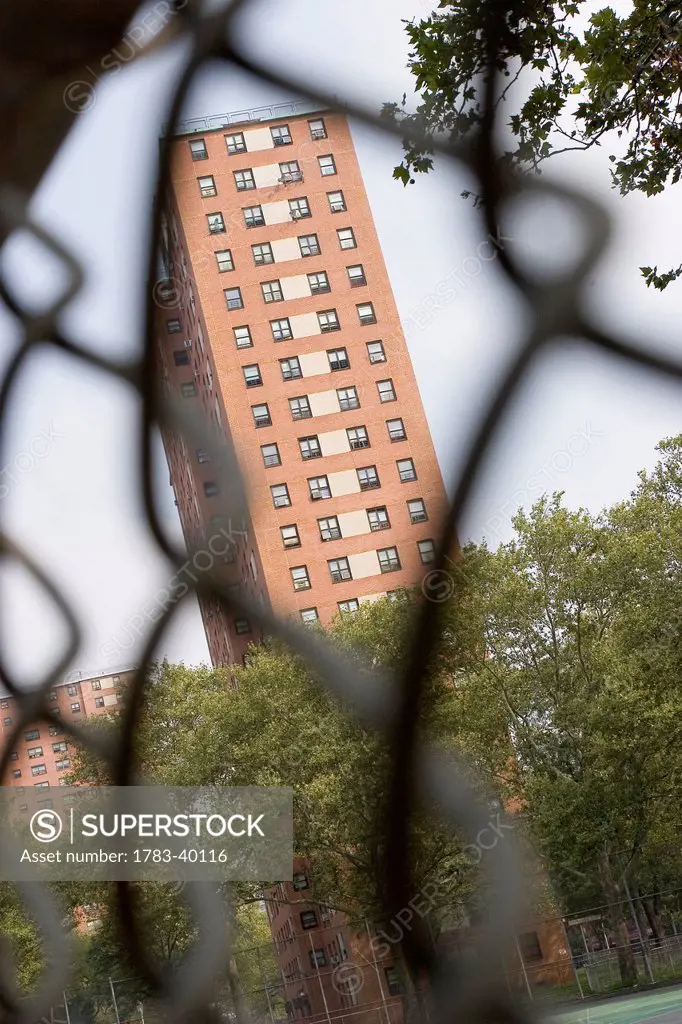 USA, New York State, New York City, Apartment building seen through chainlink fence; Harlem