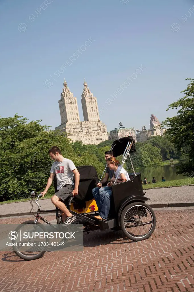 USA, New York State, Tourists in Pedicab overlooking water in Central Park; New York City