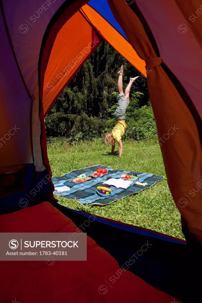 USA, New York State, Woman cartwheeling by tent at camping site; Hudson Valley