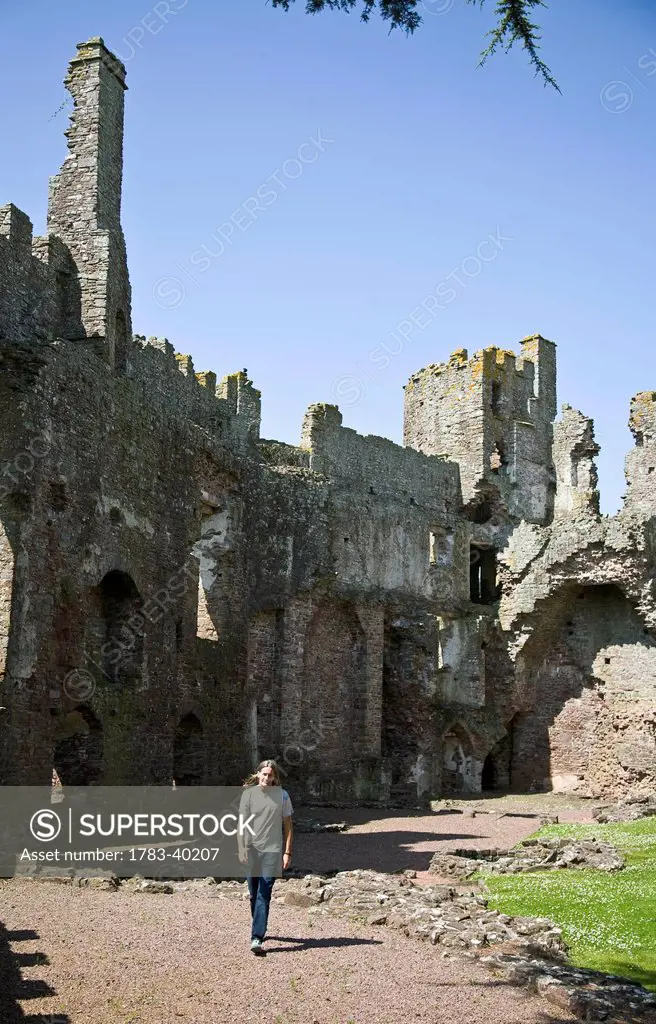 United Kingdom, Wales, Pembrokeshire, Man walking by Laugharne Castle; Laugharne