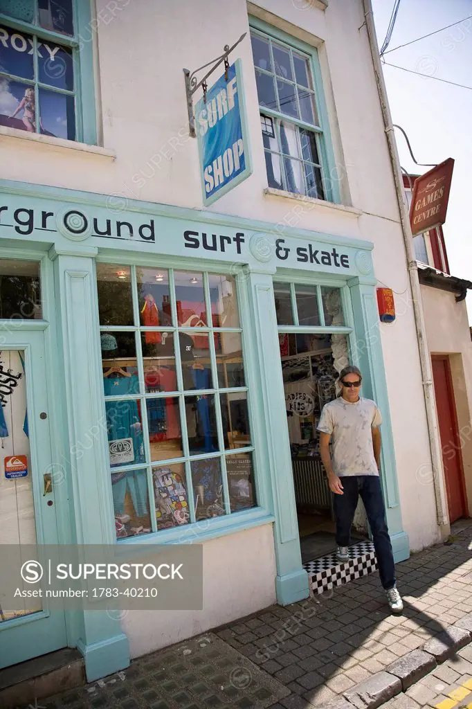 United Kingdom, Wales, Pembrokeshire, Man leaving surf shop; Saundersfoot
