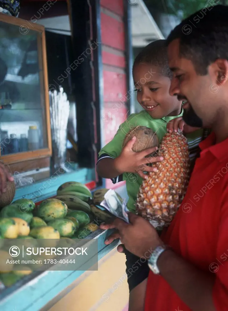 Man And Son Buying Fruit And Veg From Stall Near Speighstown On The West Coast Of Barbados.