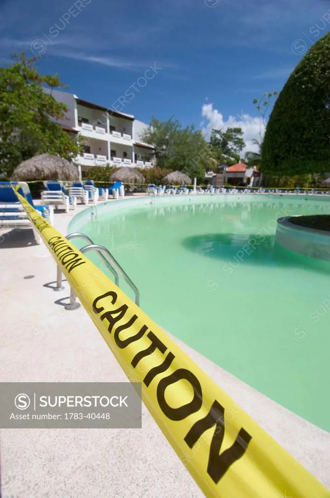 Green swimming pool roped off with 'Caution' tape, Flamenco Hotel, Puerto Plata, Dominican Republic. © Ian Cumming / Axiom