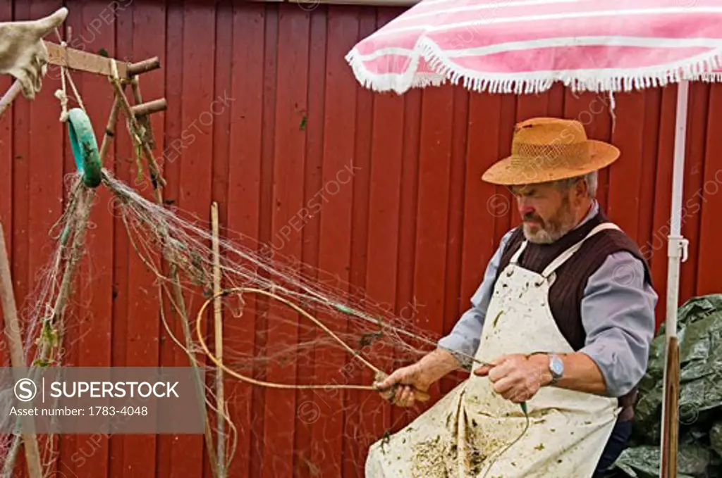 Fisherman repairing his nets Ringkobing, situated right by the inlet Ringkobing Fjord , West Jutland Denmark