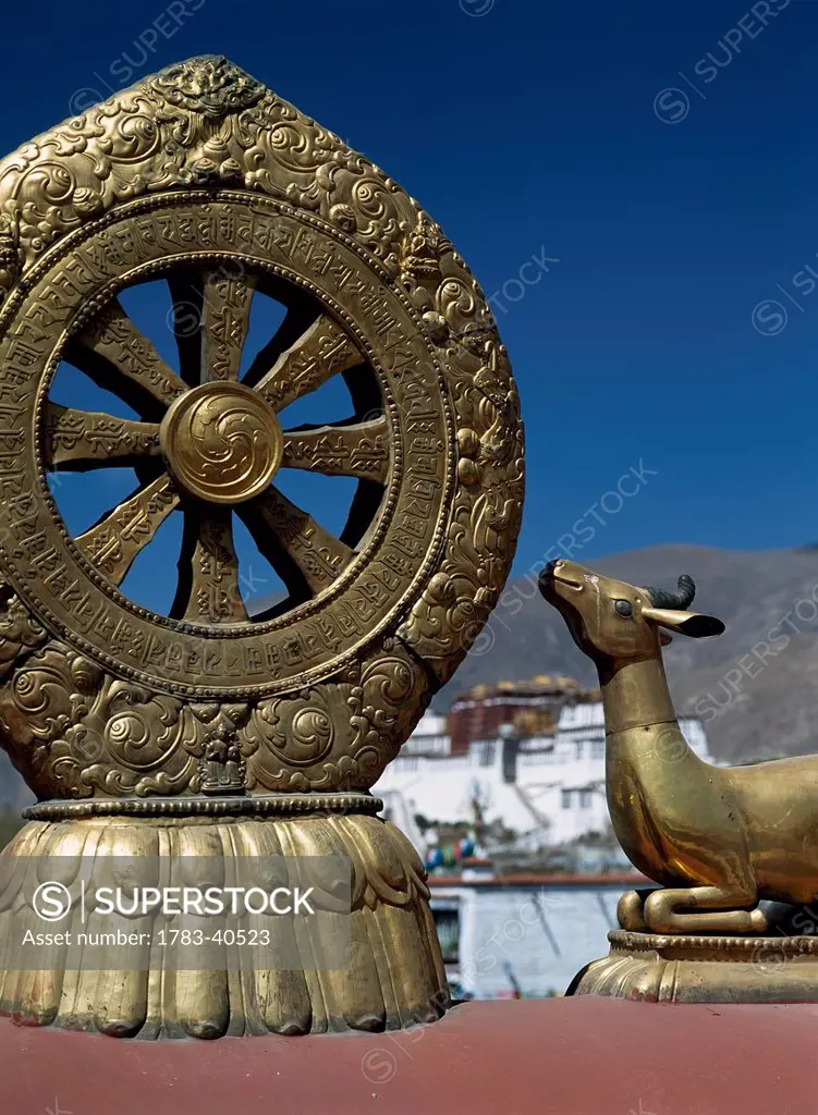 Statues Of Deer And Dharma Wheel On Top Of The Jokhang Temple With The Poata Palace In The Background, Lhasa, Tibet. © Ian Cumming /Axiom