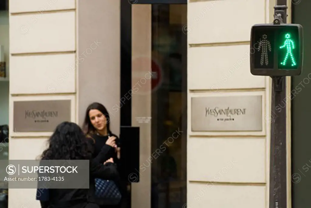 Women entering Yves Saint Laurent shop beside pedestrian crossing sign in St Germaine, Paris, France 