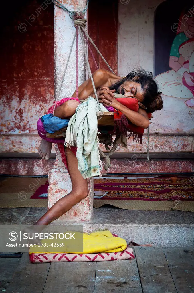 Young ascetic sleeping on rocking chair; Varanasi, India