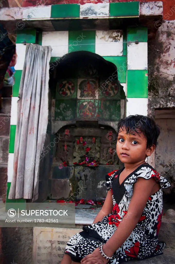 Portrait of young girl sitting by shrine; Varanasi, India