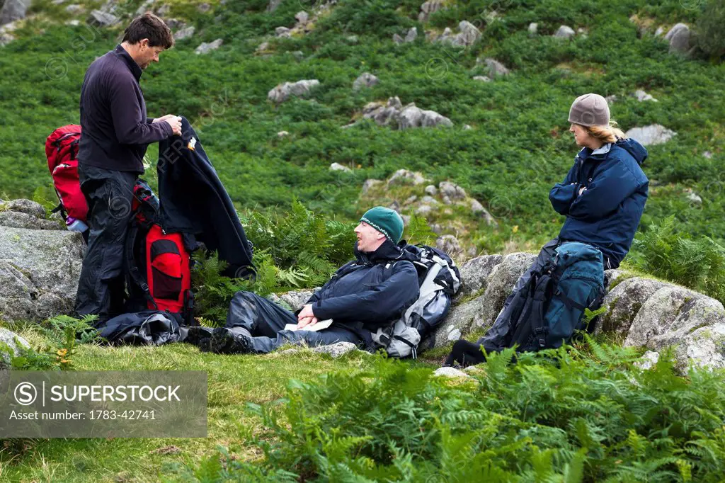 Hikers taking break from walking among hills of Western Lake District; Cumbria, England, UK