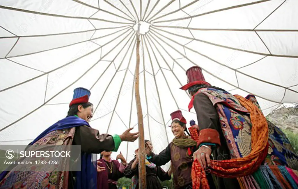 Ladakhi women in traditional dress and hats dancing under a traditional marquee, Leh, Ladakh, Indian Himalayas, India