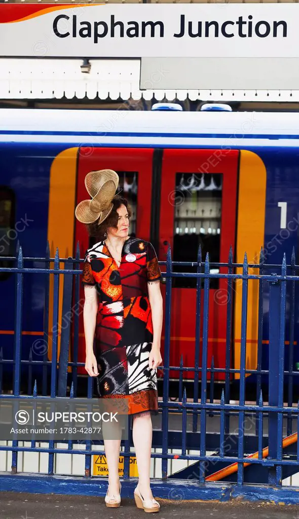 Woman at Clapham Junction waiting for train to Royal Ascot for Lady's Day; London, England, UK