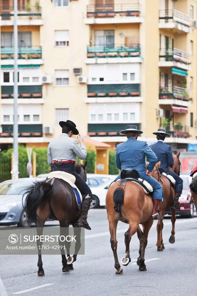 Men in traditional costume horseback riding to April Feria Festival; Seville, Andalucia, Spain, Europe