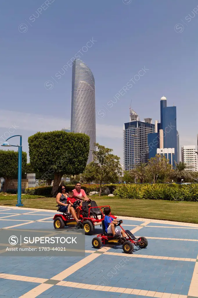 People with pedal cars on Abu Dhabi Corniche; Abu Dhabi, United Arab Emirates