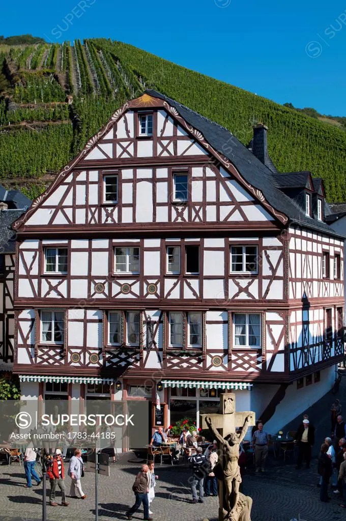 Pedestrians walking on the streets with vineyards on the slopes in the background; Bernkastel-Kues, Rhineland-Palatinate, Germany