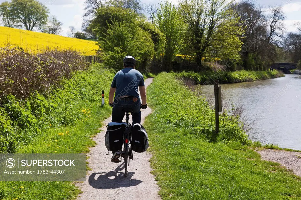 Cycling along path next to Kennet and Avon Canal; Great Bedwyn, Wiltshire, England