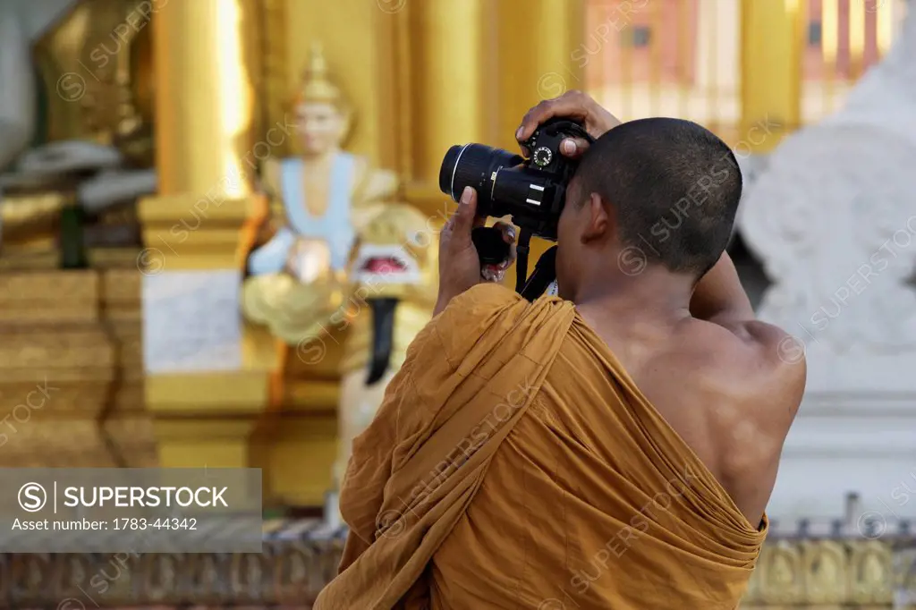 A monk takes a photograph at Shwedagon Pagoda; Yangon, Burma