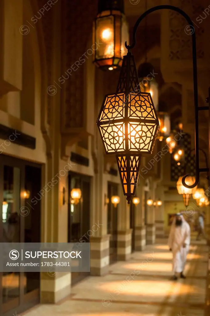 Man in traditional arabic dishdasha outfit walking along corridor in shopping mall; Dubai, United Arab Emirates
