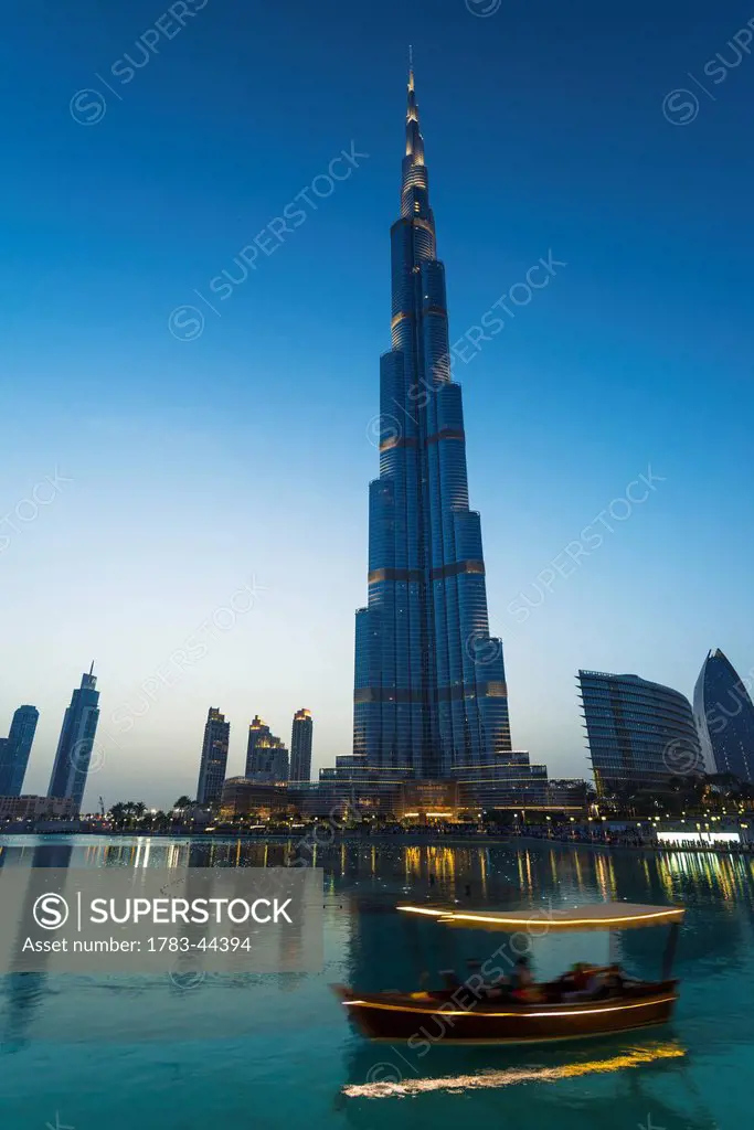Boat going around artificial lake at sunset in front of the Burj Khalifa; Dubai, United Arab Emirates