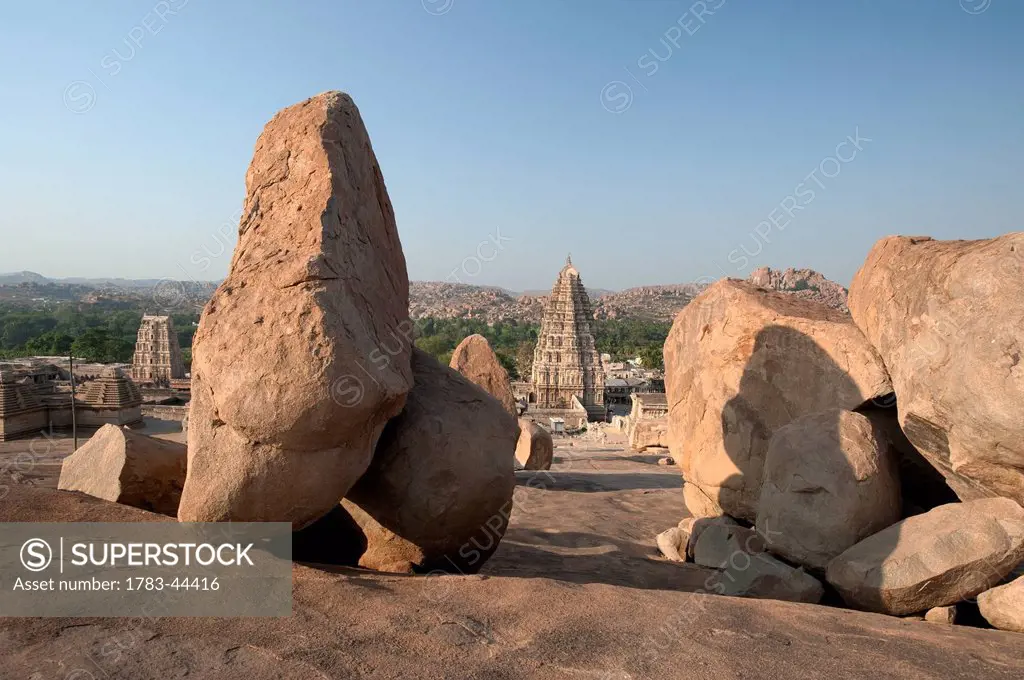 Large rocks with religious buildings in the background; Hampi, Karnataka, India