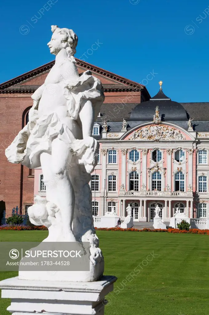 Statue and building with ornate facade against a blue sky; Trier, Germany