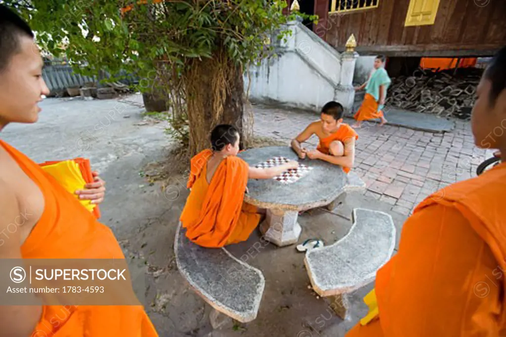 Novice monks relaxing playing checkers, Luang Prabang, Northern Laos