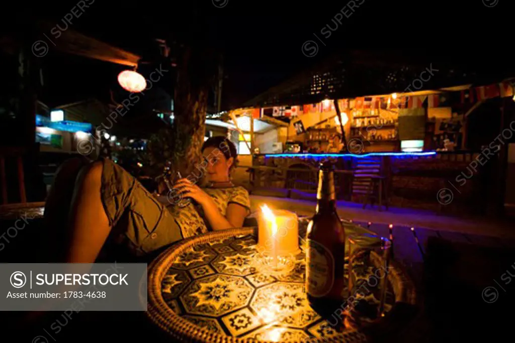 Young woman sitting in bar at night in Vang Vieng, Laos