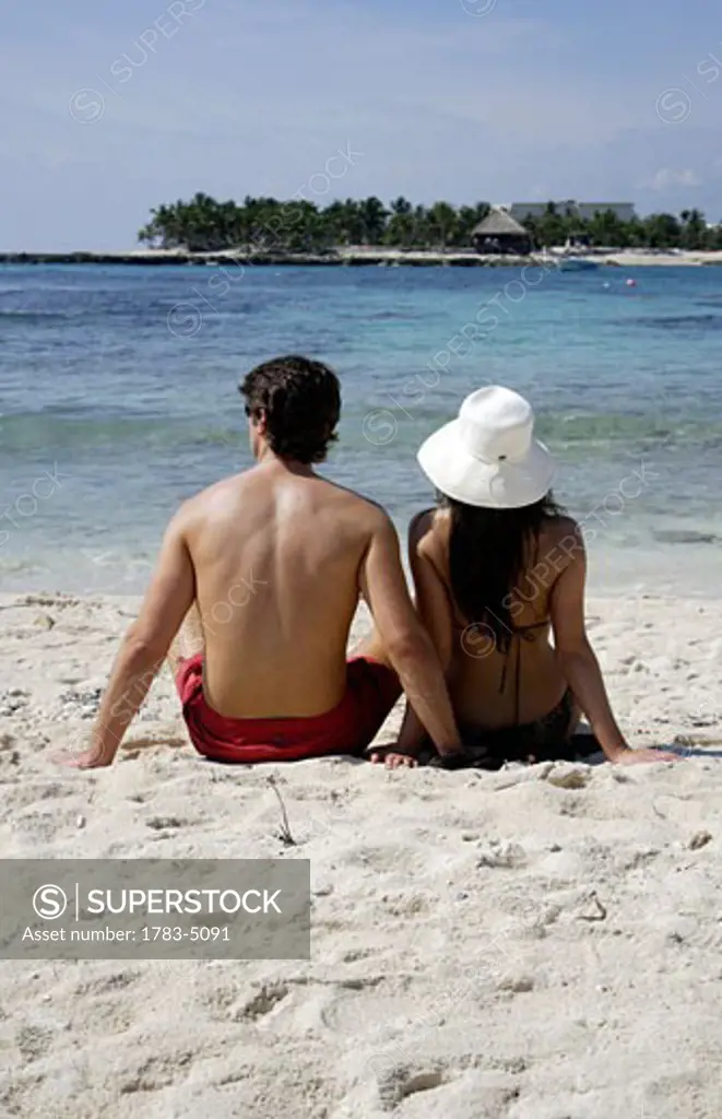 Young couple sitting on beach at Mayan Riviera,rear view, Yucatan Peninsular,Quintana Roo State,Mexico