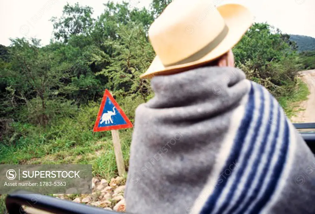 Man in safari car / jeep watching  in Shamwari Game Reserve & elephant road sign,Eastern Cape,South Africa.  