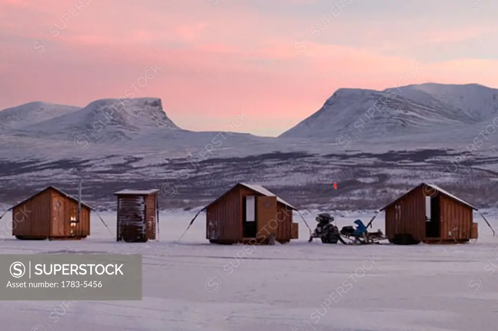 Abisko Ark Hotel cabins with Lapporten mountain range in background at dusk, Abisko,Sweden