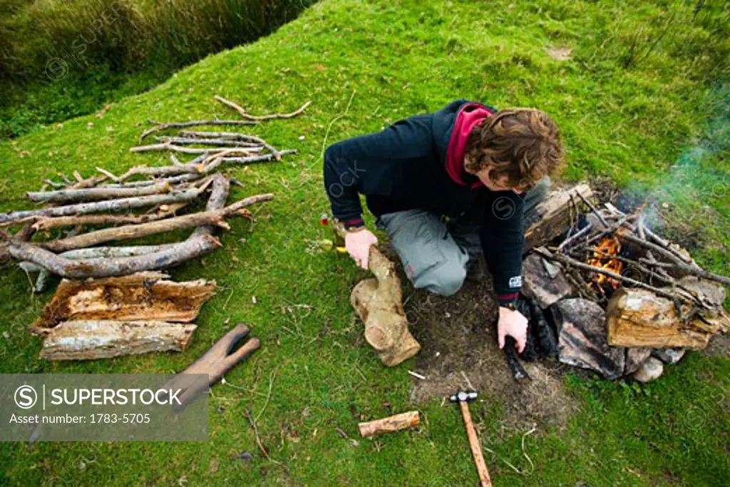 Man preparing camp fire in field, Dartmoor National Park,Postbridge,Yelverton,Devon,UK
