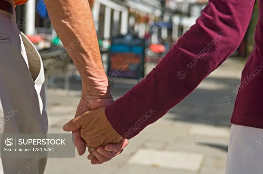 Senior couple holding hands,mid section, Pantiles,Tunbridge Wells,Kent,UK