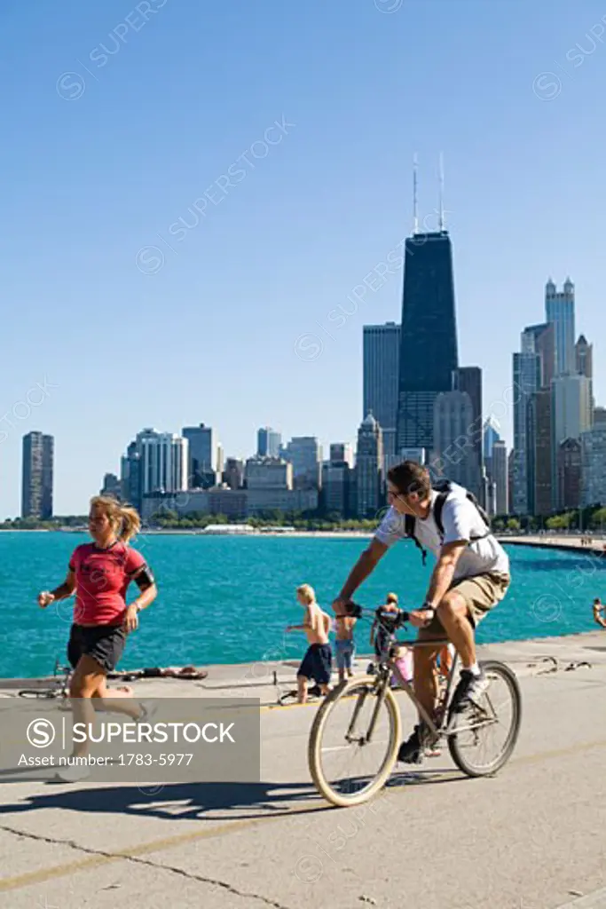 Jogger and cyclist on lakefront path along Oak Street Beach, Chicago, Illinois, USA