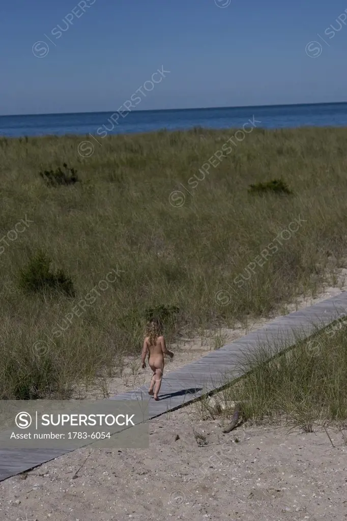 Naked girl walking along boardwalk towards sea, Peconic,North Fork,Long Island,New York,USA