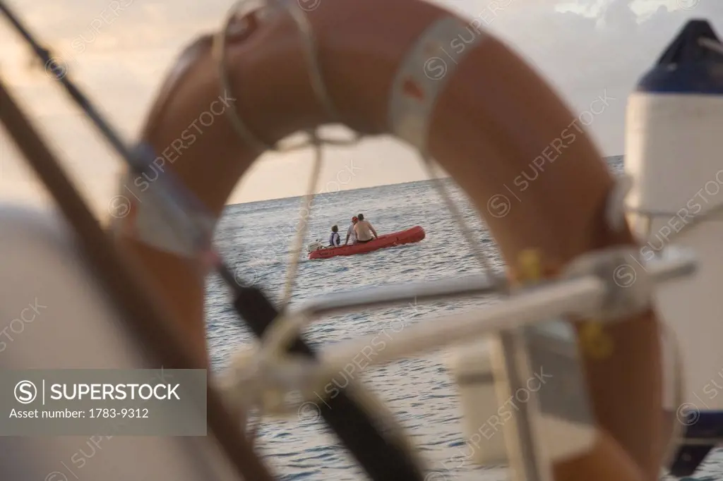 Boy and men in boat as seen through life ring, Whitsunday Islands, Queensland, Australia