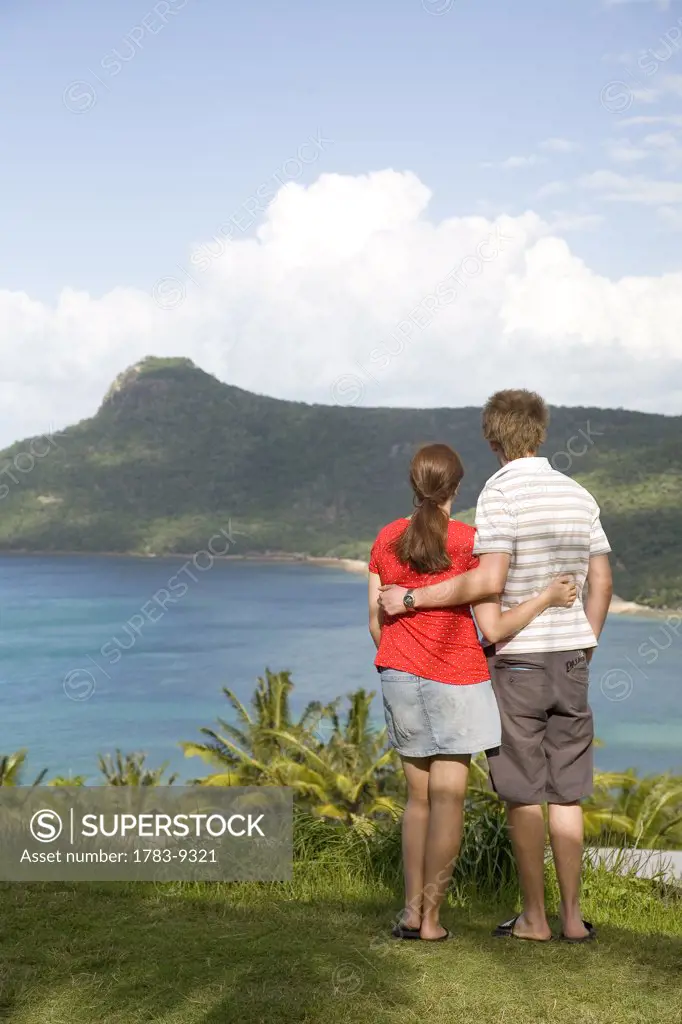 Couple at edge of cliff looking at coastline, Whitsunday Islands, Queensland, Australia