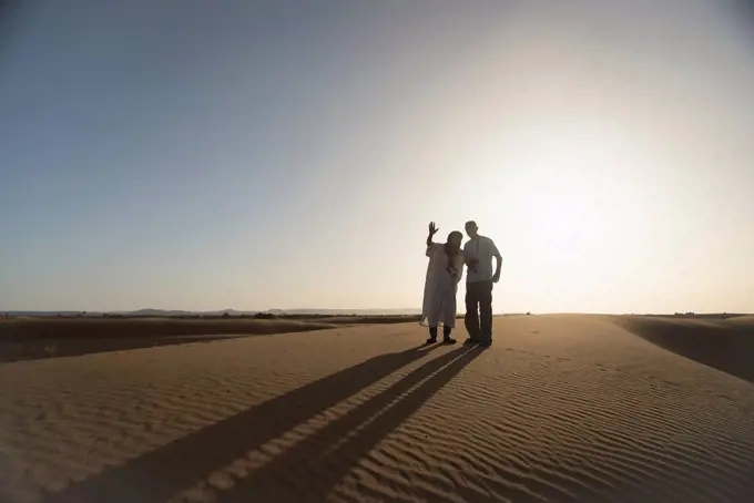Silhouettes of desert guide and tourist at sunset; Merzouga, Morocco