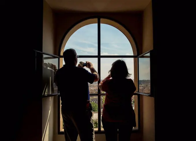 Tourists taking photographs from a window inside The Vatican; Rome, Italy