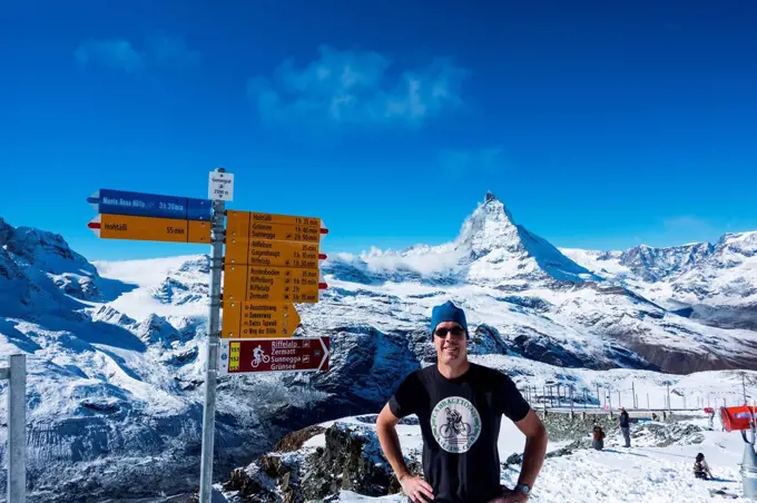 A male tourist poses at the Gornergrat Kulm hotel and observatory with the Matterhorn in the background; Switzerland