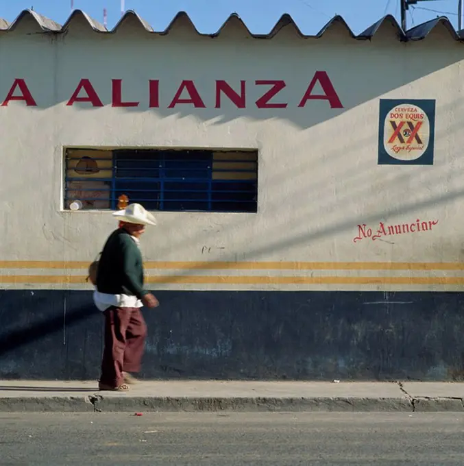 Man passing bar with guitar, Oaxaca, Mexico