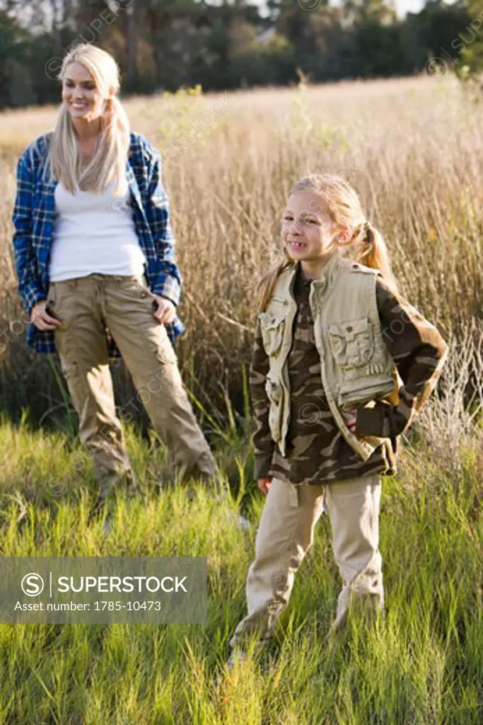 Mother and daughter standing in grass in outdoor clothing