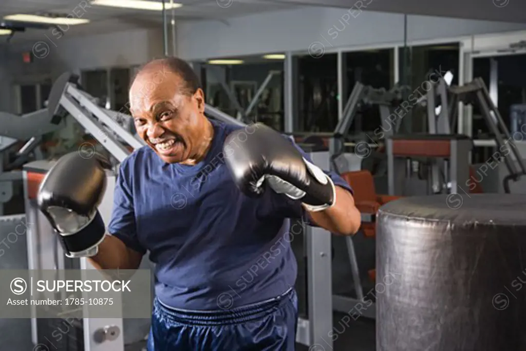 Portrait of senior man with boxing gloves at gym