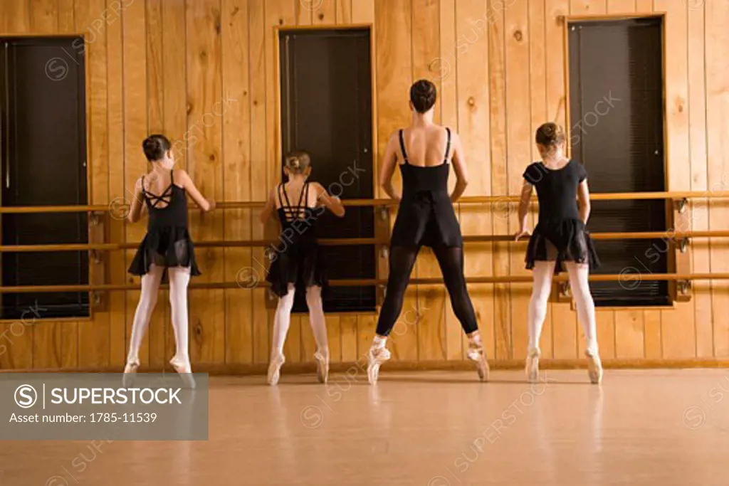 Young ballerinas with instructor in dance studio having lesson