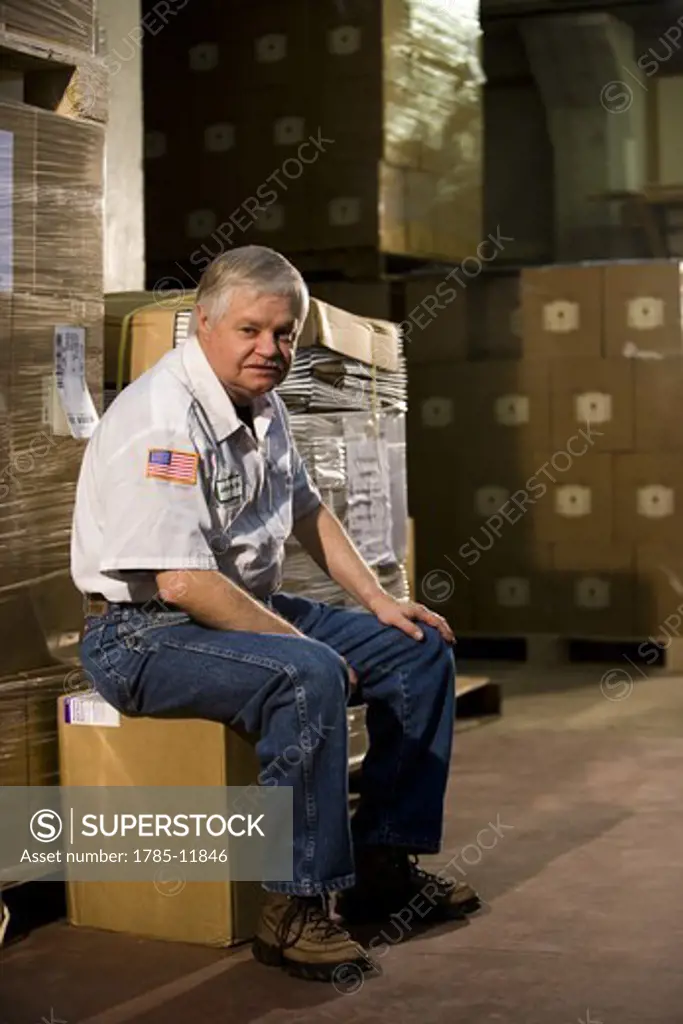 Male worker sitting on a box in a storage warehouse