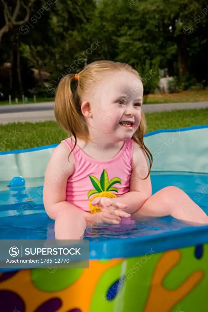 Side view of a girl with downs syndrome playing in kiddie pool