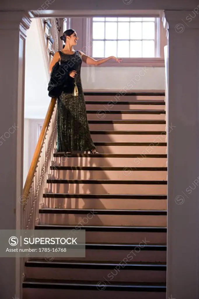 Hispanic woman in formal gown standing on stairs