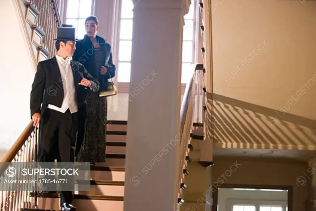 Well-dressed couple walking down stairs for a night out