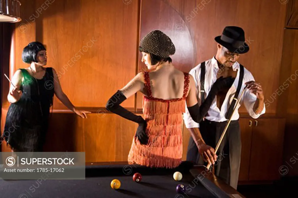 African American man playing billiards as woman in flapper dress touches him
