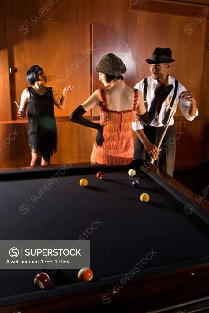 African American man playing billiards with flapper girls