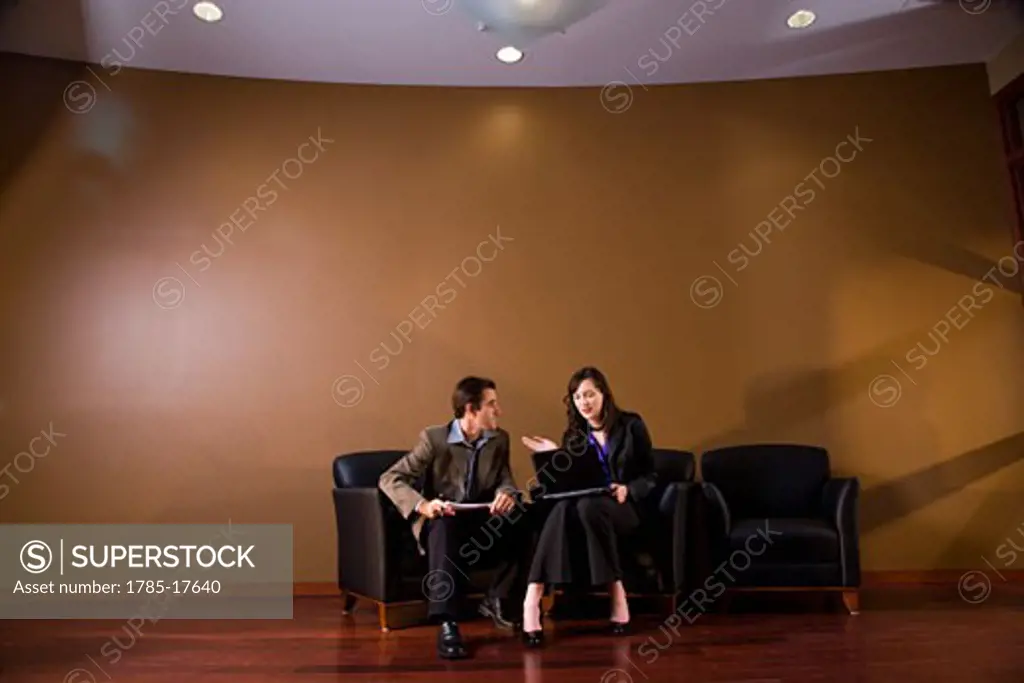 Two business people in lounge area  working together on laptop